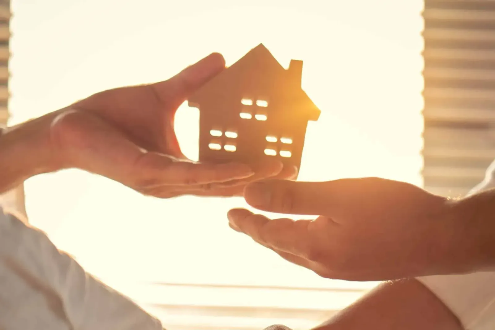 Hands holding a small model house against the light